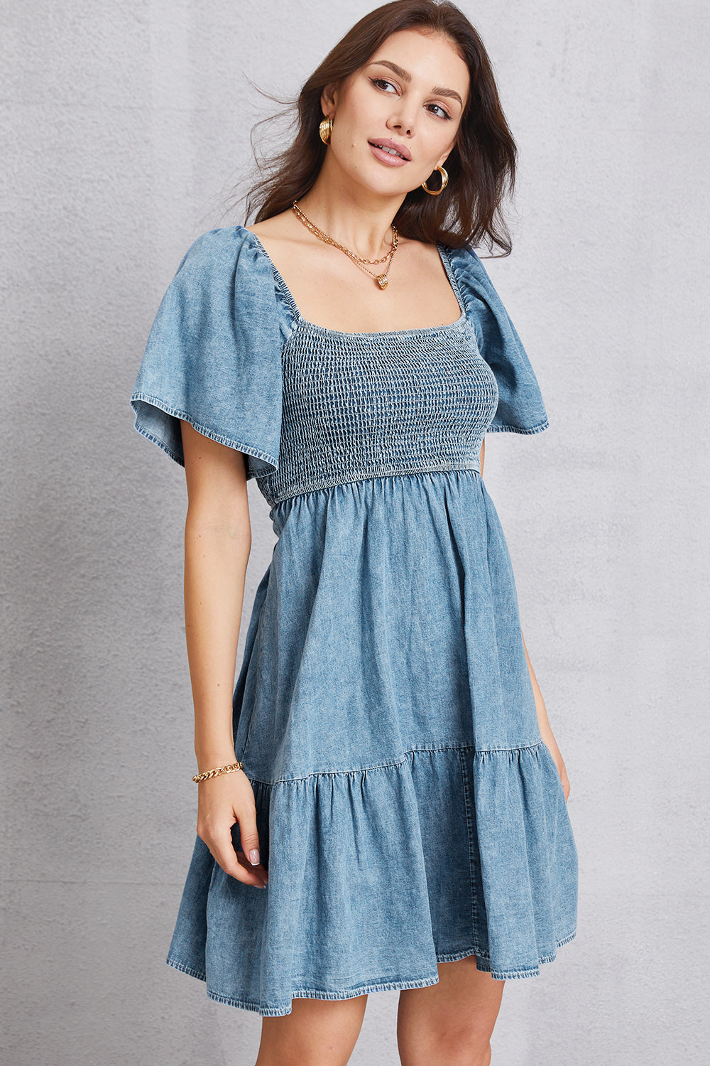 VYSN smocked square neck mini denim dress displayed on a hanger, showcasing its stylish design and fitted bodice.