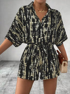 Striped button-up belted romper jumpsuit by Trendsi with long sleeves and a waist tie, featuring a stylish striped pattern.