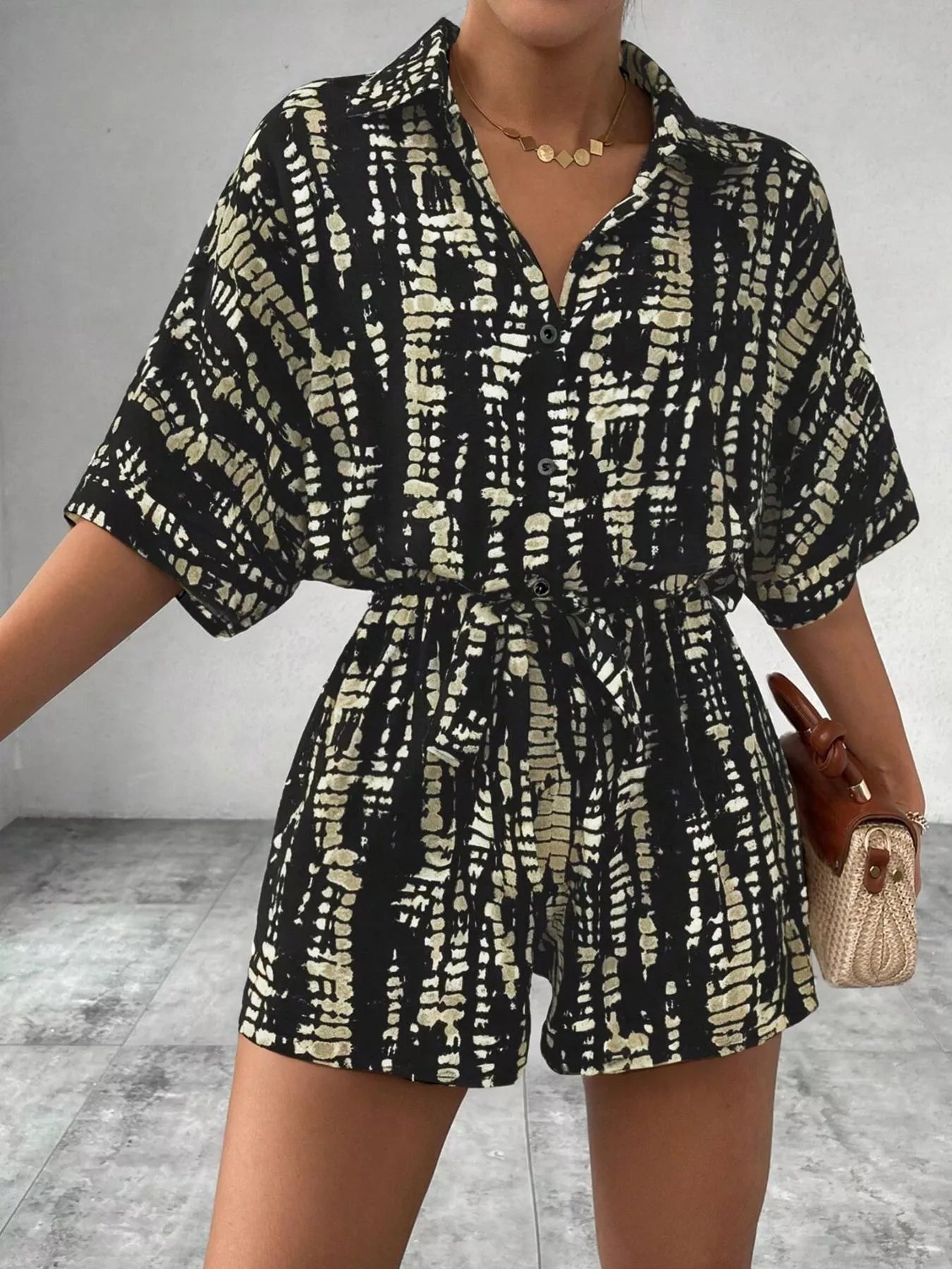 Striped button-up belted romper jumpsuit by Trendsi with long sleeves and a waist tie, featuring a stylish striped pattern.