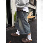 Vintage distressed wide-leg denim shorts in a faded blue wash, featuring front utility pockets and a loose fit.