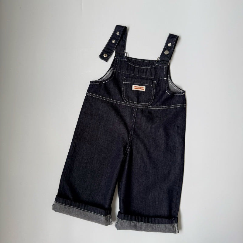 Dark blue denim overalls with cuffed hems, contrast stitching, front chest pocket with small label, and metal snaps.