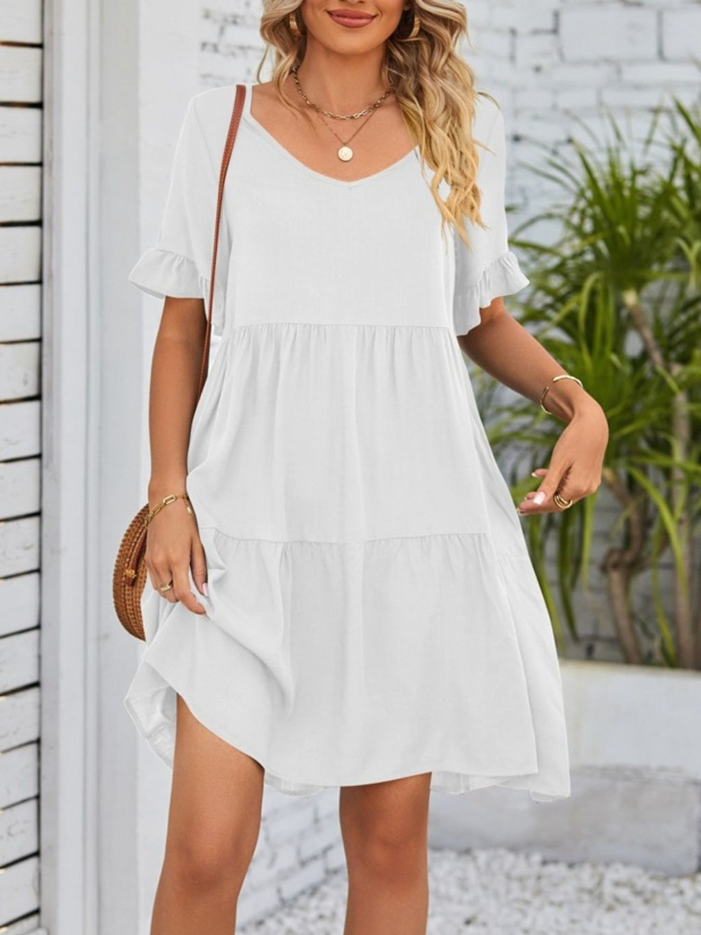 Lightweight rayon mini dress with ruffled sleeves, tiered design, and pockets, featuring a stylish and feminine look.