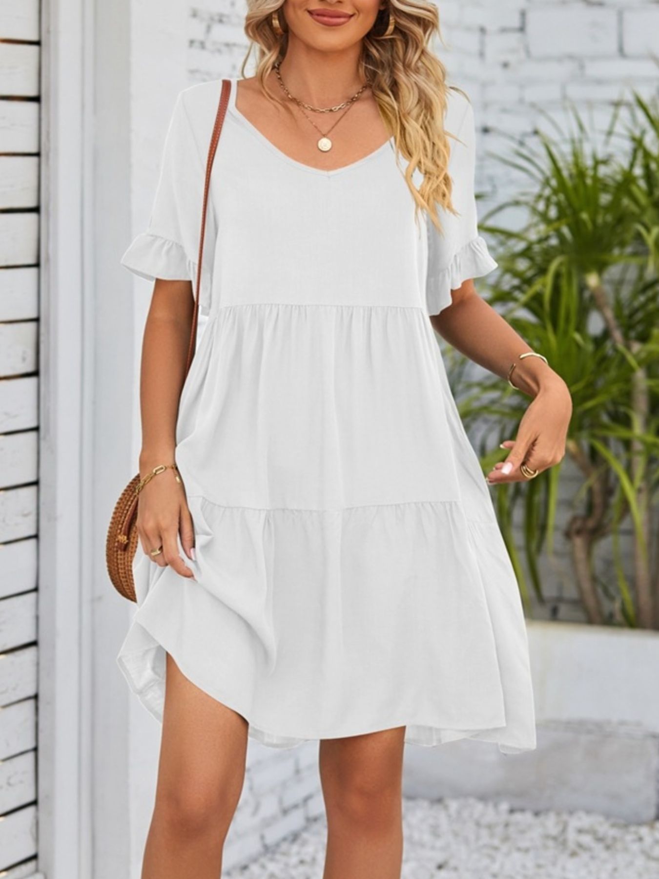 Lightweight rayon mini dress with ruffled sleeves, tiered design, and pockets, featuring a stylish and feminine look.