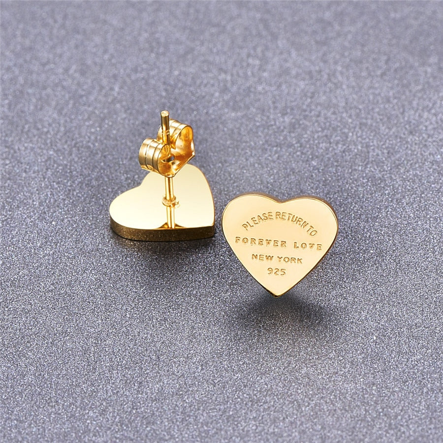 Gold-tone heart stud earrings with engraved text "PLEASE RETURN TO FOREVER LOVE NEW YORK 925" and push backs.