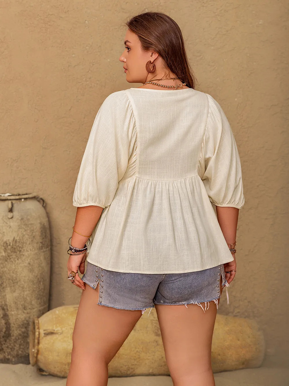 Plus size V-neck half sleeve peplum blouse from Trendsi, featuring a flattering fit and stylish design, shown on a model.