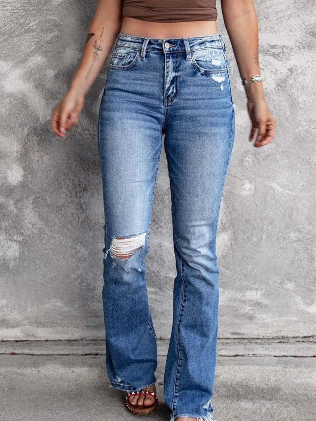 Distressed flare denim jeans from Plush Fashion Shop featuring ripped details and a high-waist fit, styled with a casual look.