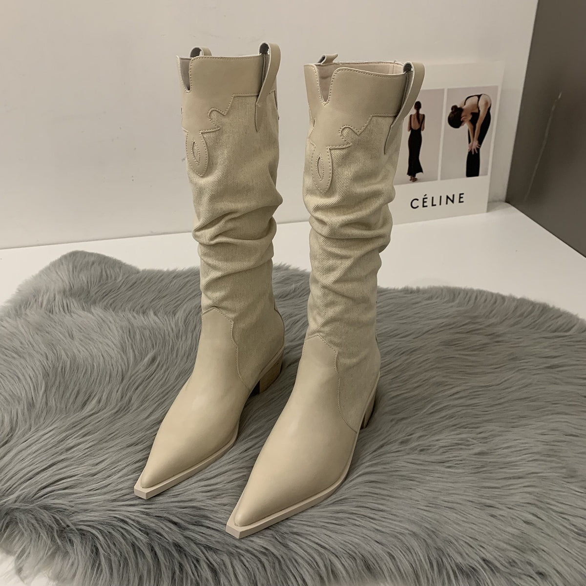 Beige leather and canvas slouchy western boots with pointed toes and embroidered shafts on a grey rug.