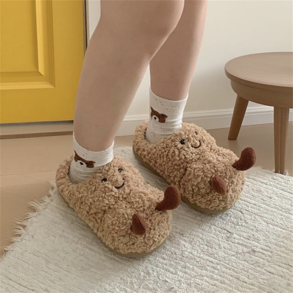 Fluffy brown fleece slippers with embroidered smiling faces, deer antlers, worn with white socks.