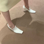 White leather square-toe stiletto mules with a textured finish and architectural heel.