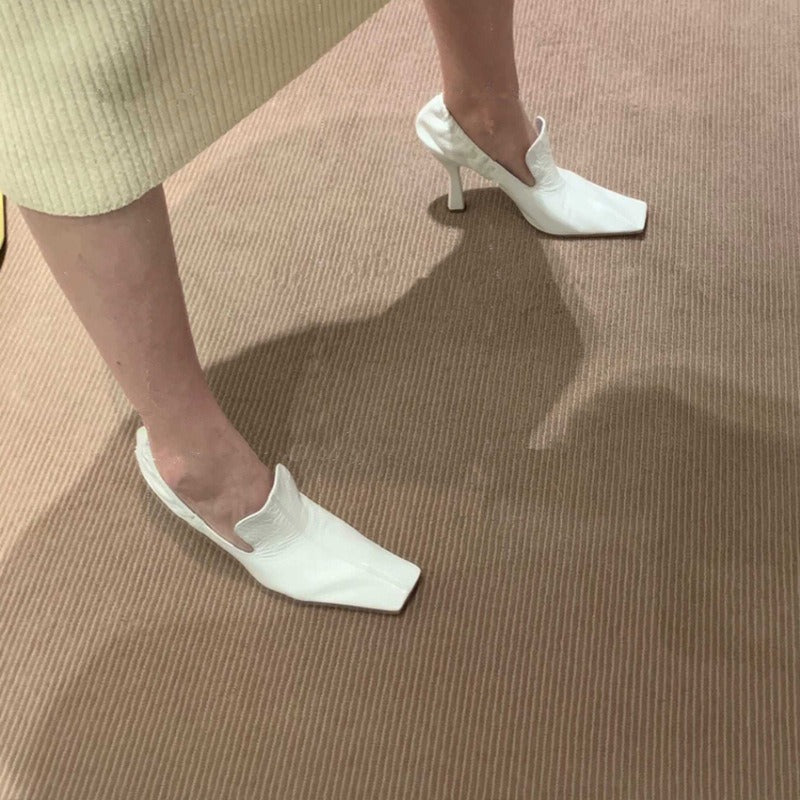 White leather square-toe stiletto mules with a textured finish and architectural heel.