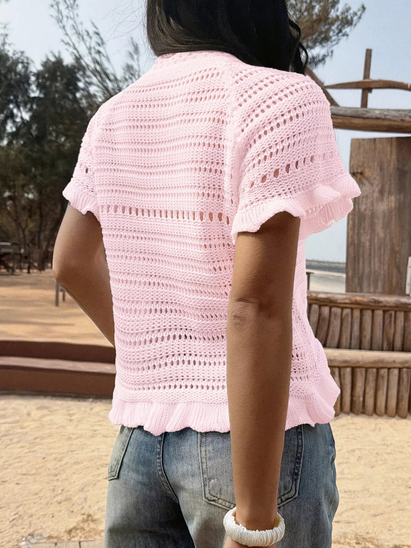 Openwork ruffled hem knit top by Trendsi featuring a stylish design with openwork details and a ruffled hem for a trendy look.