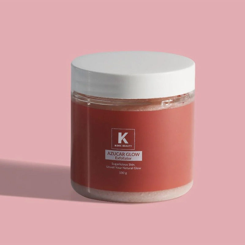 A clear plastic jar with a white lid containing pink Azucar Glow Exfoliator, featuring a red label with white text.