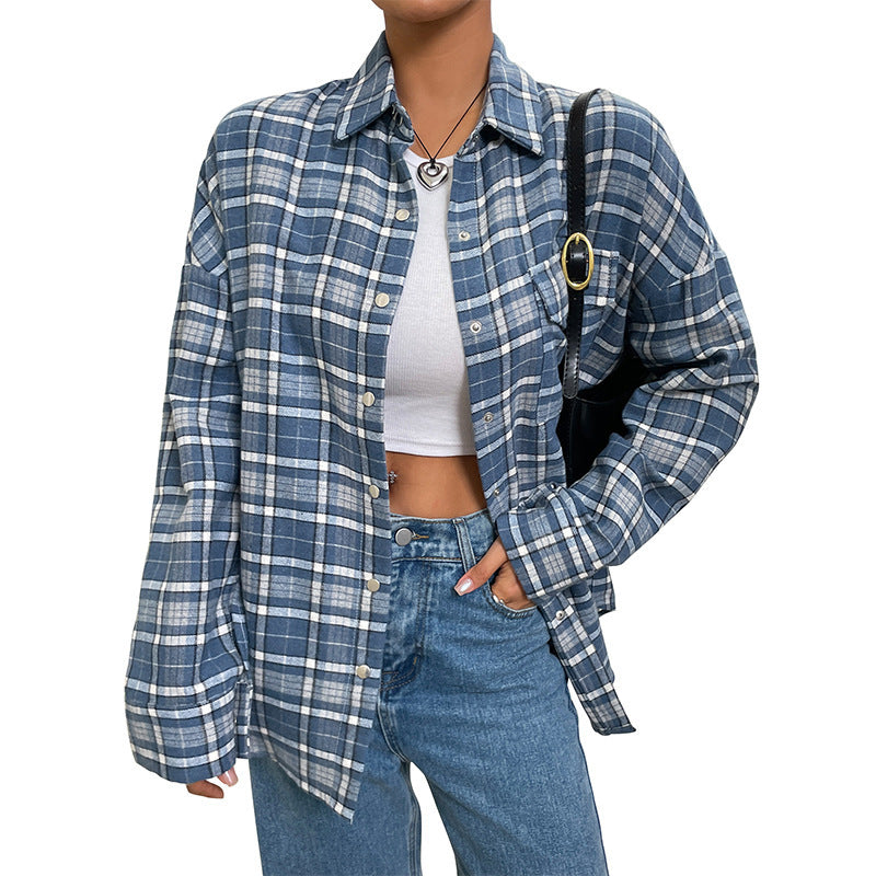 An oversized blue and white plaid flannel button-down shirt worn open over a white crop top and jeans.