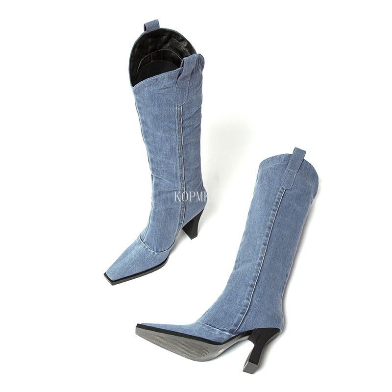 Blue denim knee-high boots with pointed toes, pull tabs, and black stiletto heels.