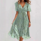 Floral print FitiqueFit A-line dress with V-neck, short sleeves, midi length, worn by a model in a bright outdoor setting.