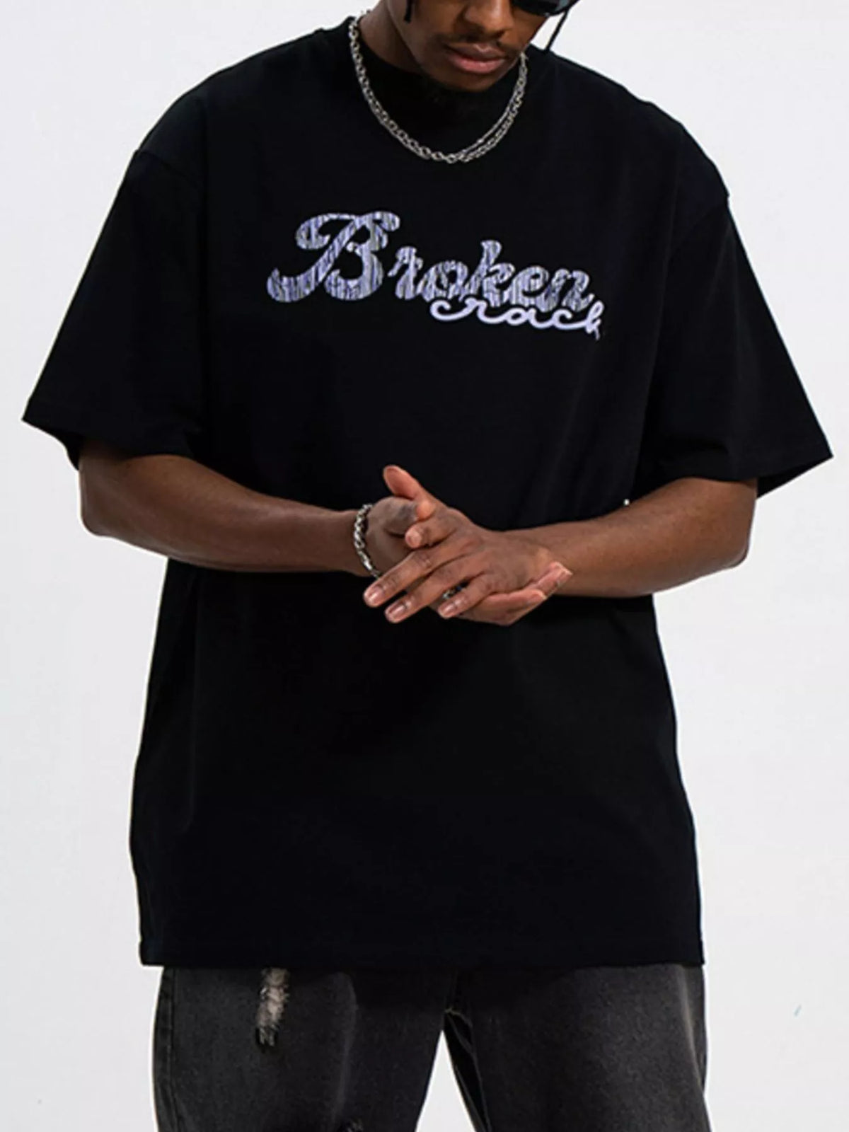 Men's oversized graphic round neck T-shirt by Trendsi, featuring bold print design on soft fabric, casual and comfortable fit.