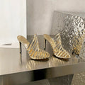Elegant gold sheepskin cage-style stiletto heels with metallic straps and a clear side panel.