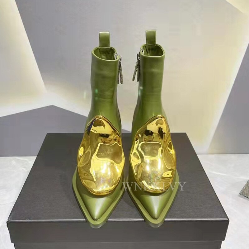 Olive green leather ankle boots with pointed toes and sculptural, reflective gold metal caps over the toes.