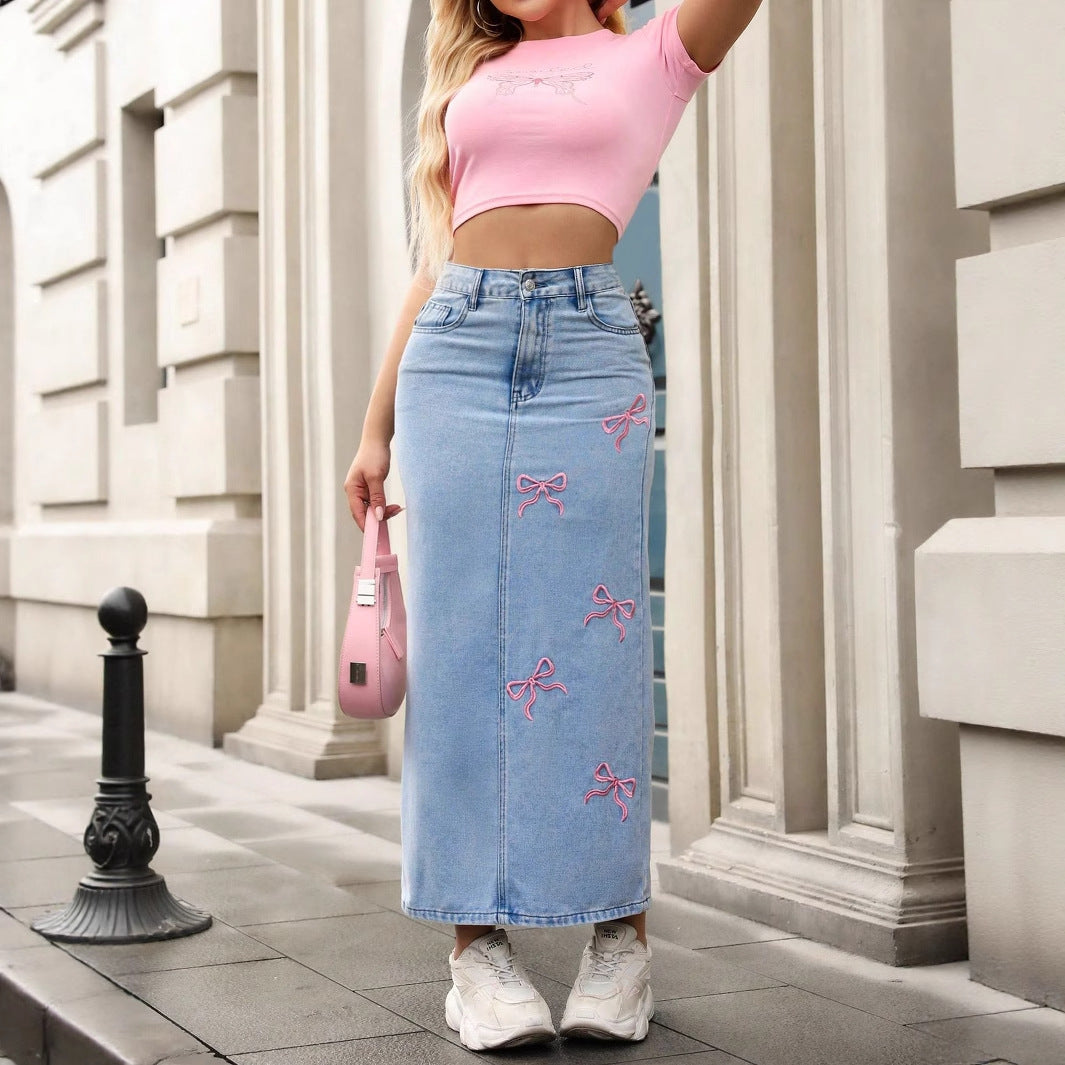 Light blue denim maxi skirt with pink bow embroidery, straight style, high waist, and front seam.