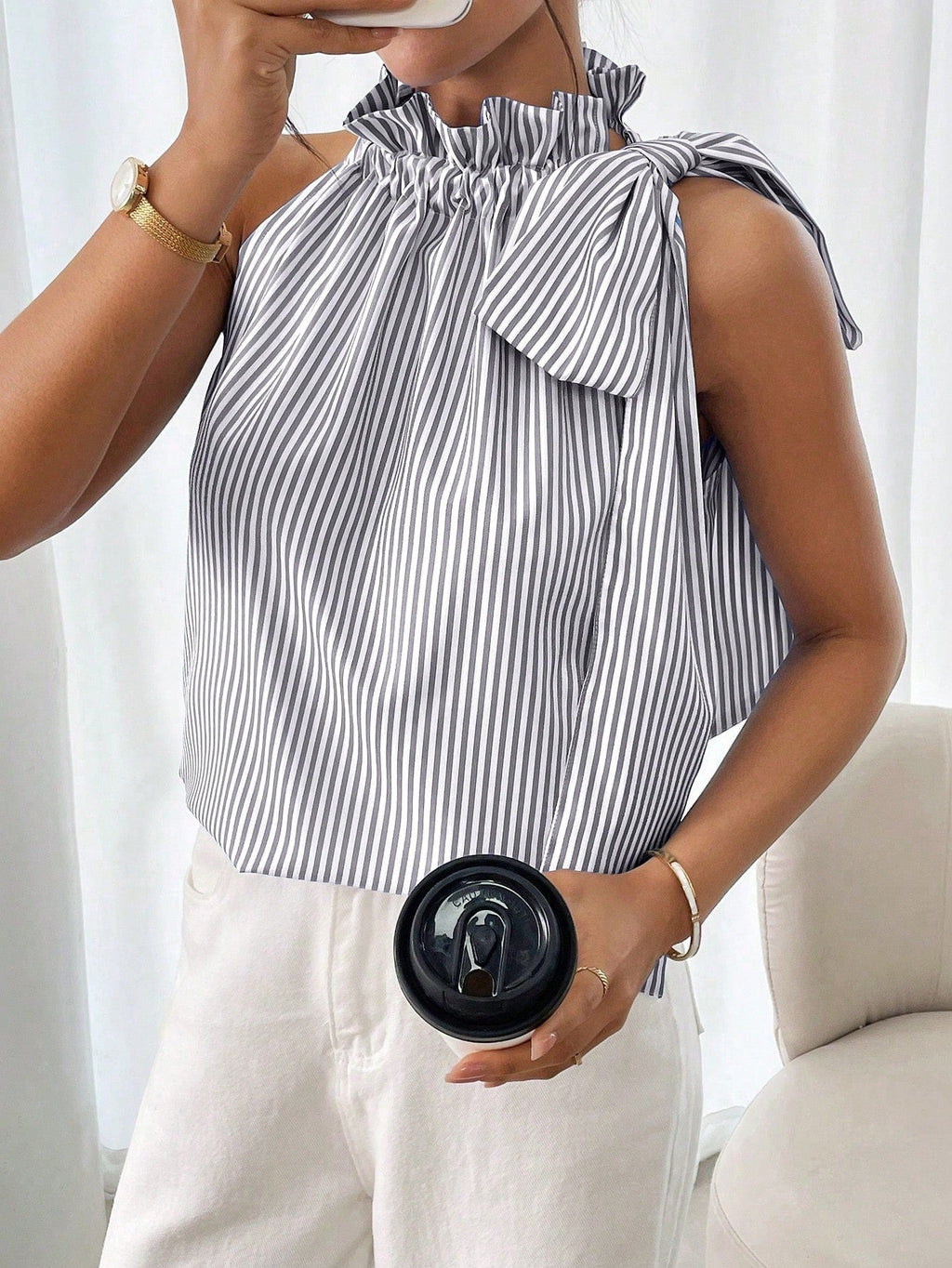 Women's sleeveless striped blouse by Plush Fashion Hub with ruffle high neck, lace trim, and tie-knot bow detail.