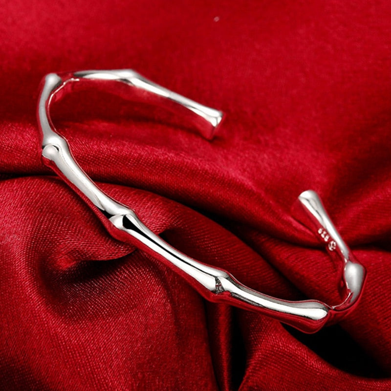 Silver bamboo-shaped cuff bracelet on a red fabric background.