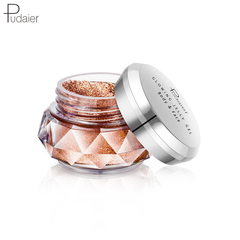 Open jar of bronze body and face glitter gel in a faceted clear container with a silver lid.