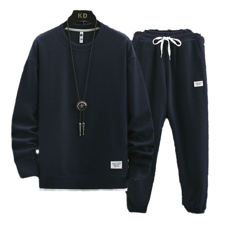 Navy blue waffle knit tracksuit with white drawstrings, layered hem, and small rectangular label details.