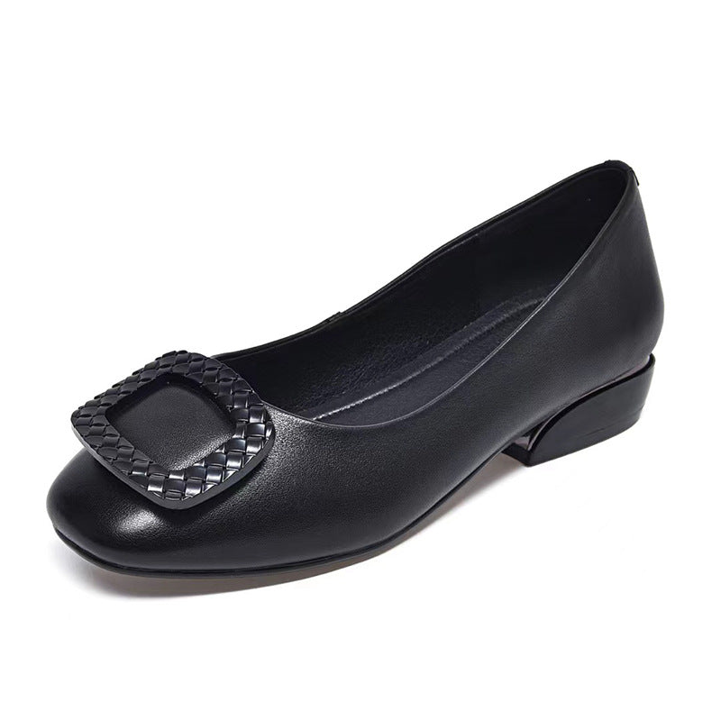 Black leather low-heel pump with a woven square buckle on the toe and a round toe style.