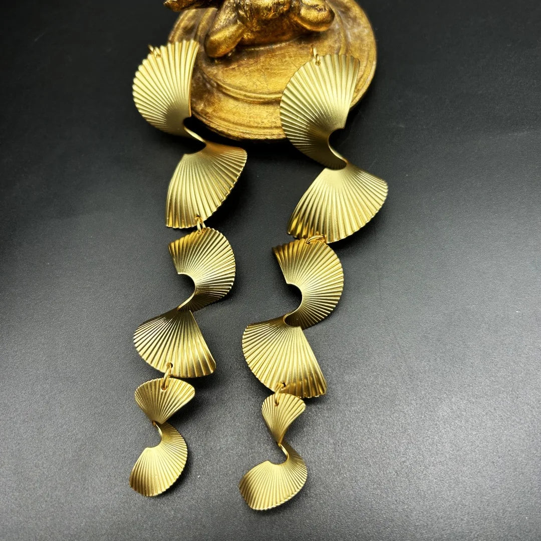 Gold drop earrings with a ribbed, pleated fan pattern in a tiered metal style.