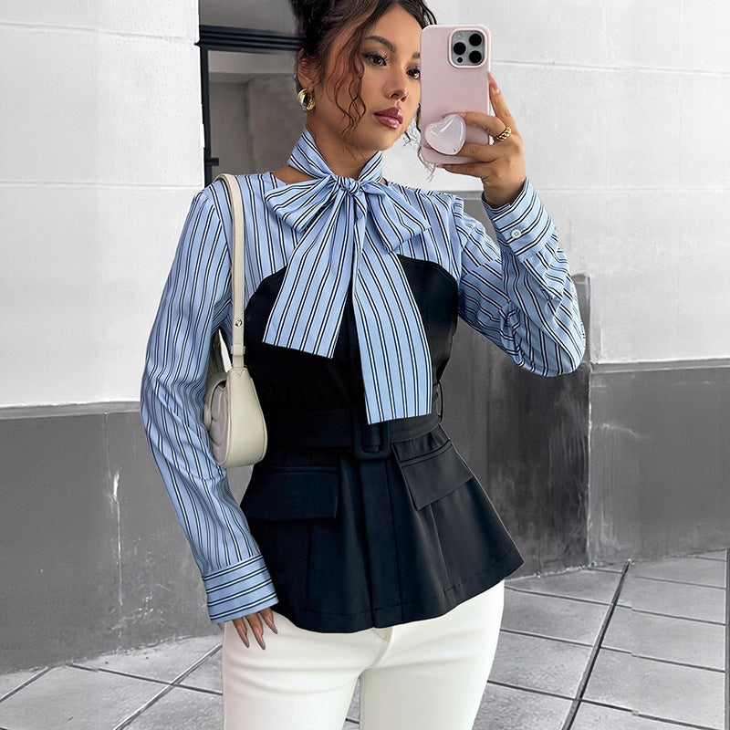 A woman wearing a blue and white striped blouse with a black bustier, bow tie, belted peplum waist, and flap pockets.