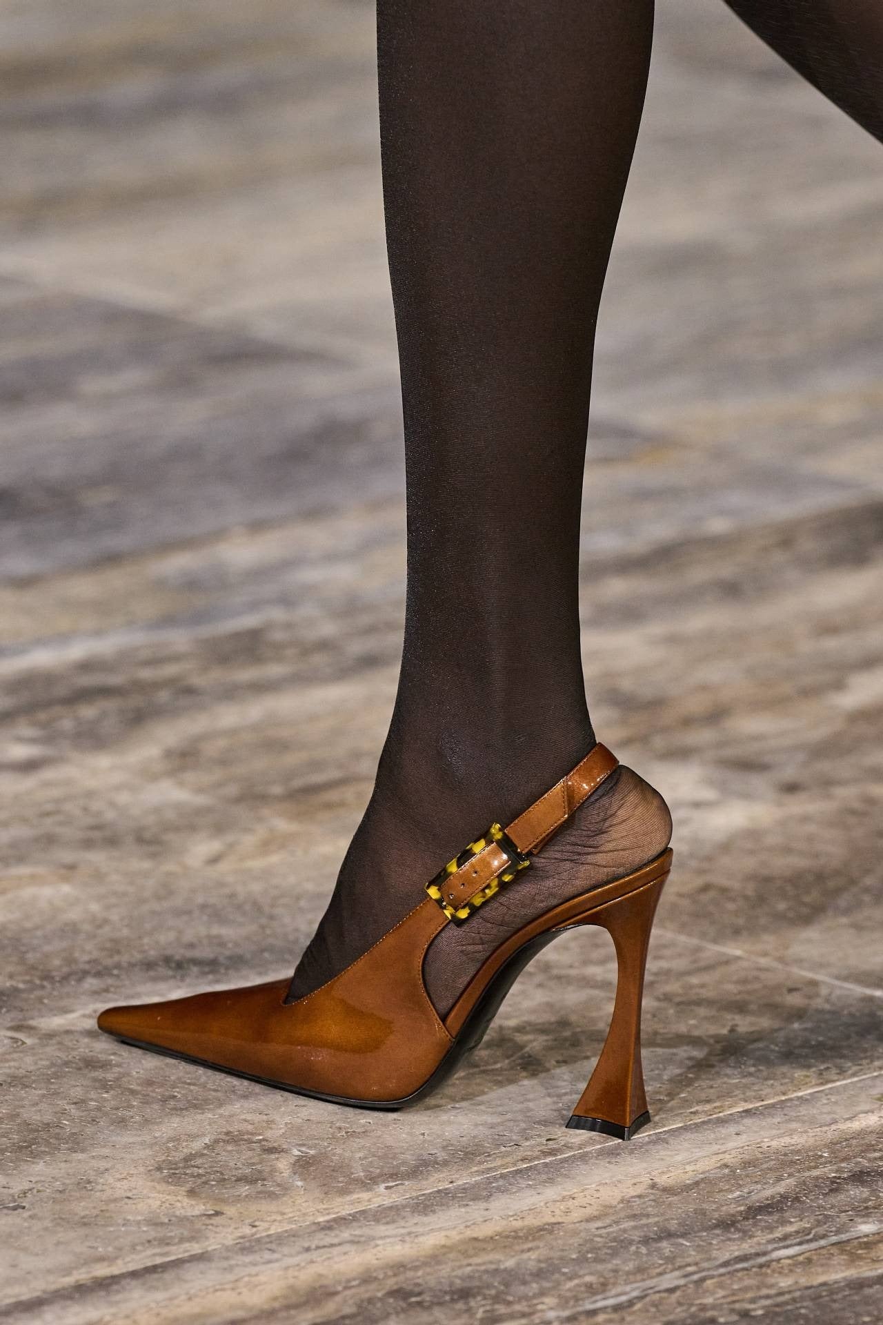 Tan patent leather slingback heels with a pointed toe, flared stiletto heel, and a tortoiseshell buckle.