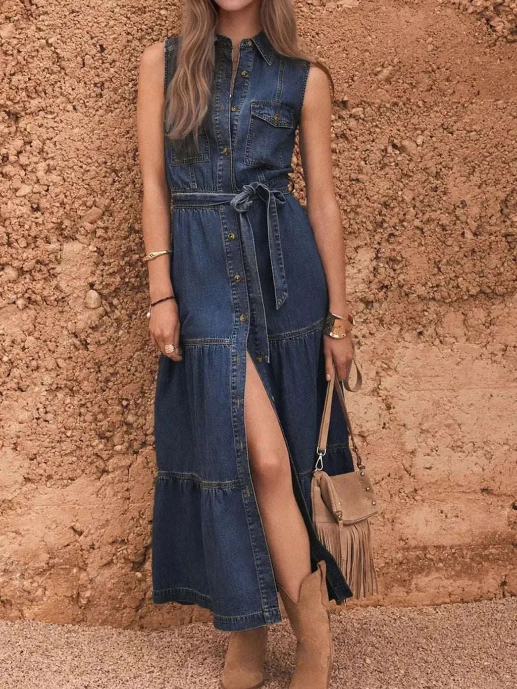 Sleeveless denim dress by Trendsi featuring button-front closure, tiered design, and matching belt for a stylish casual look.