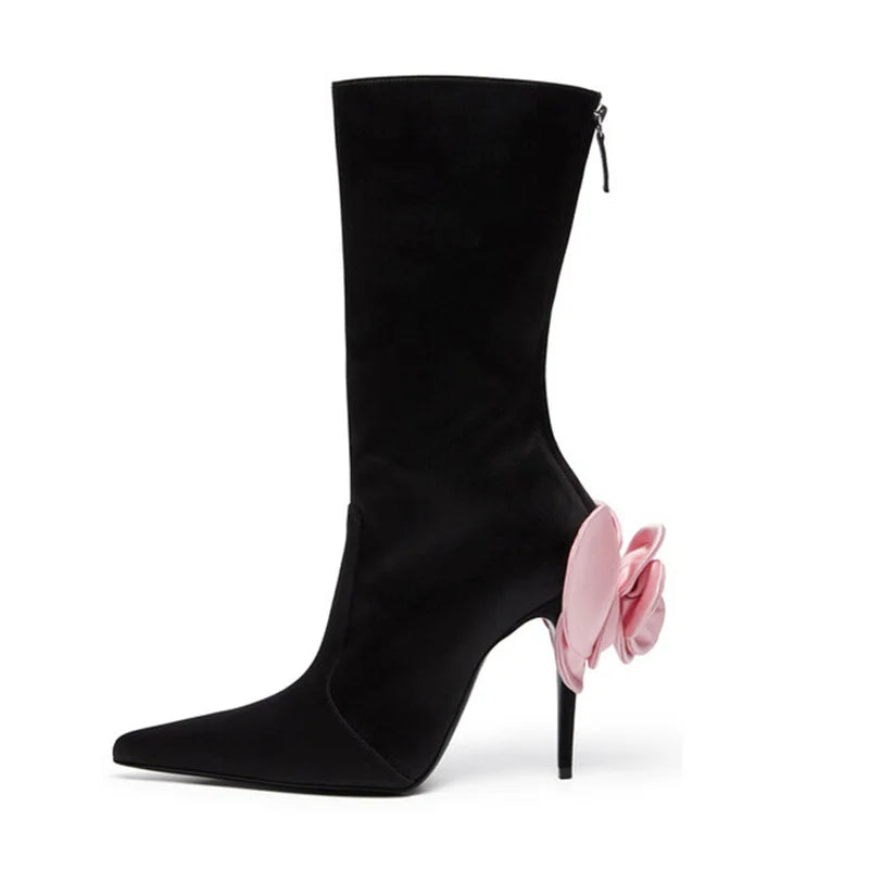 Black satin stiletto heeled boot, pointed toe, mid-calf height, featuring a large pink satin flower on the heel.