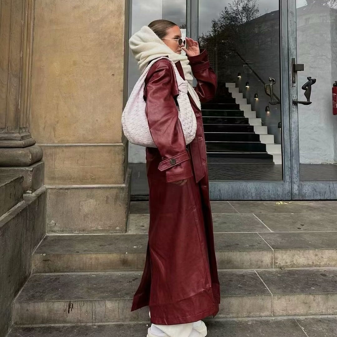 Burgundy faux leather trench coat with button cuffs, paired with a white woven handbag and scarf.