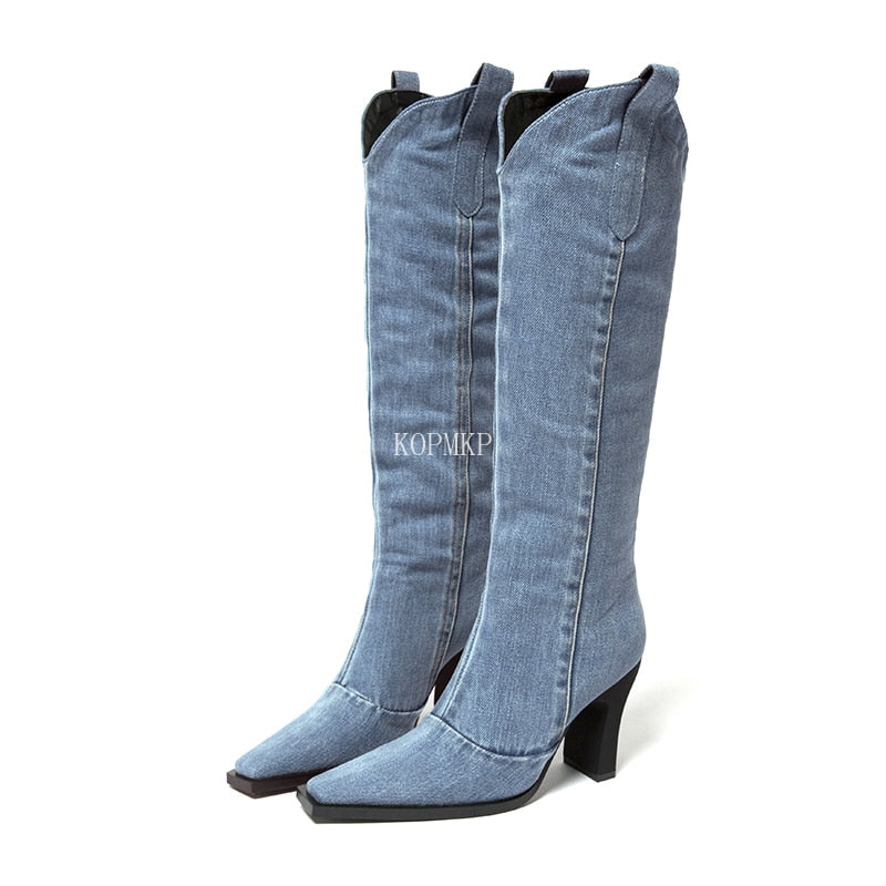 Blue denim knee-high boots with pointed toes, block heels, and pull tabs.