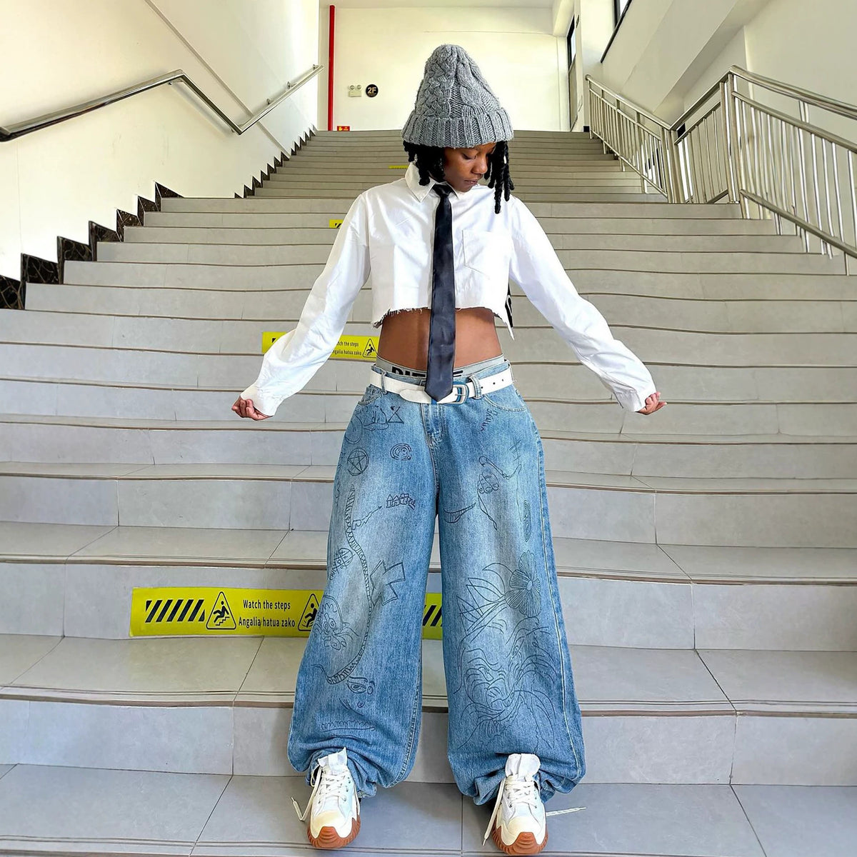 Pair of washed denim jeans with graffiti print by Plush Fashion Hub, showcasing a casual and trendy streetwear style.