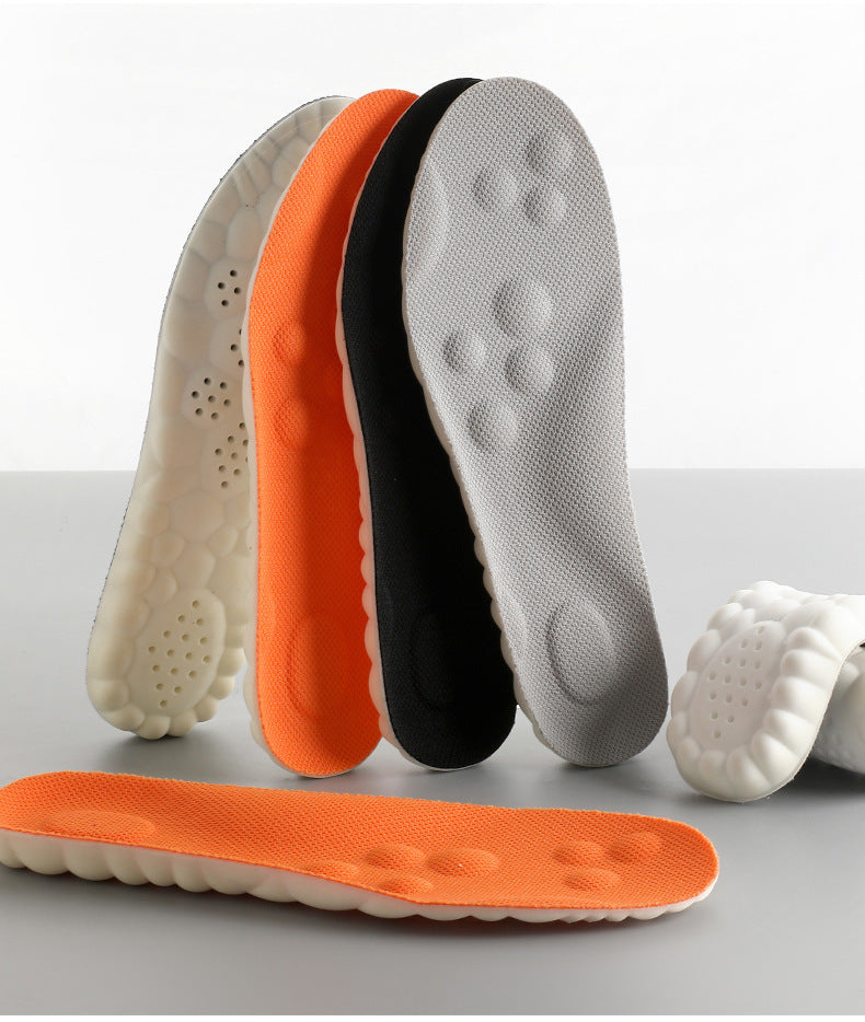 Four cushioned shoe insoles in white, orange, black, and grey stand upright, with two more laid flat.