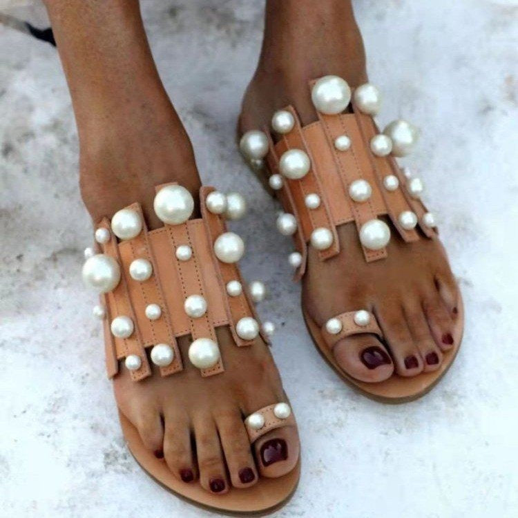 Pearl-embellished Plush Fashion Hub beach toe loop flat sandals on sandy surface with decorative pearl details.