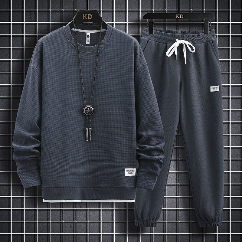 Dark gray waffle-knit tracksuit with crewneck sweatshirt, white drawstring joggers, and a pendant necklace.
