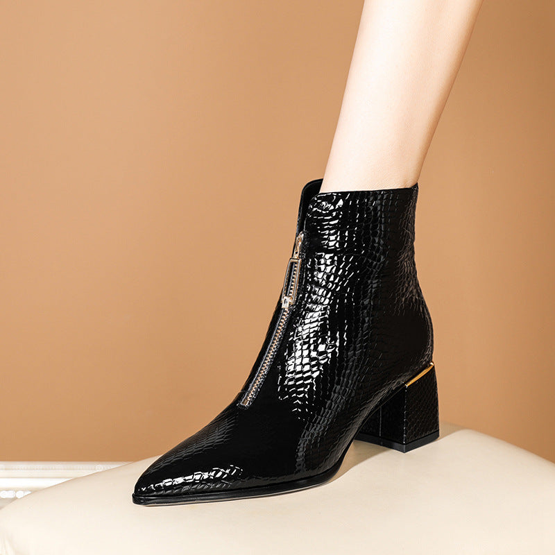 Glossy black patent leather ankle boot with embossed snake pattern, front zipper, pointed toe, and block heel.