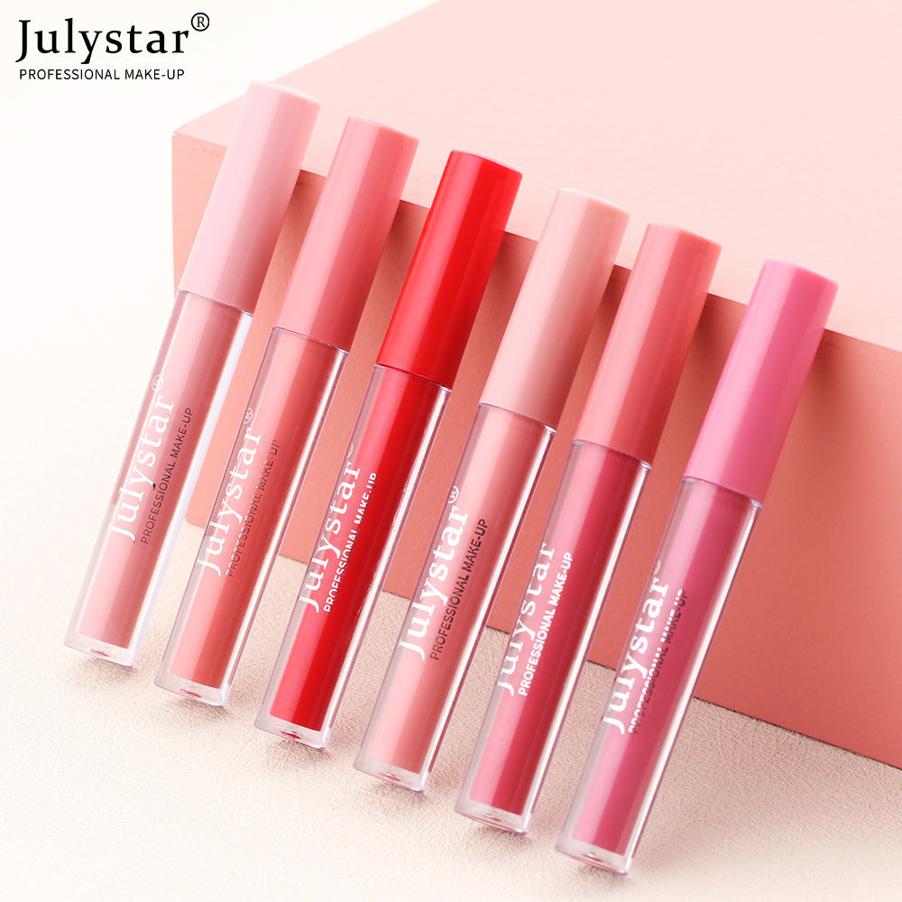 Six Julystar lip glosses with translucent tubes and matching colored caps, lined up in various pink and red shades.