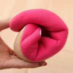 Hand holding a flexible, minimalist indoor slipper with a hot pink cotton interior and a tan suede-like outer sole.