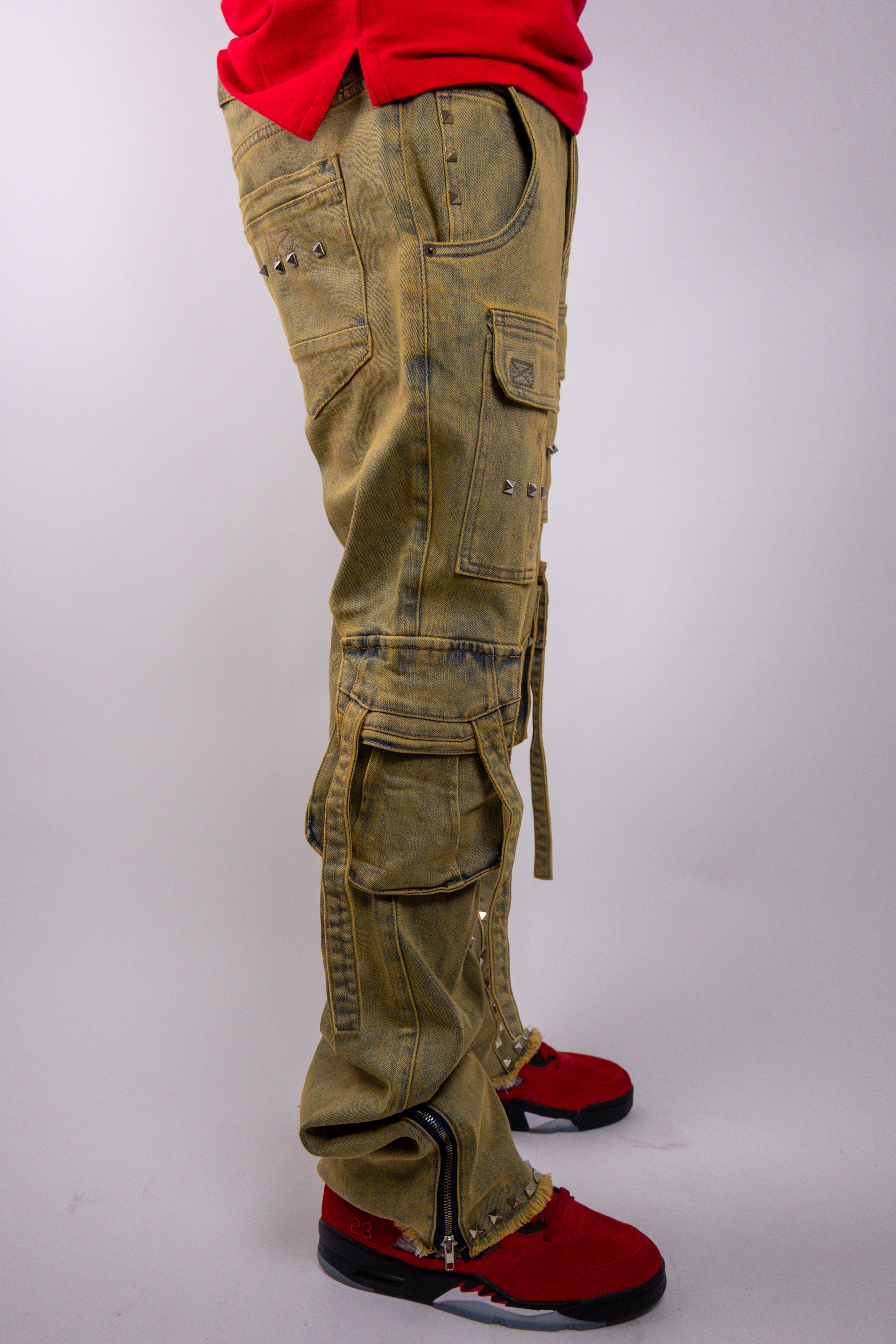 ARMOR JEANS studded stacked cargo jeans with multiple pockets and distressed details, shown in a close-up view.