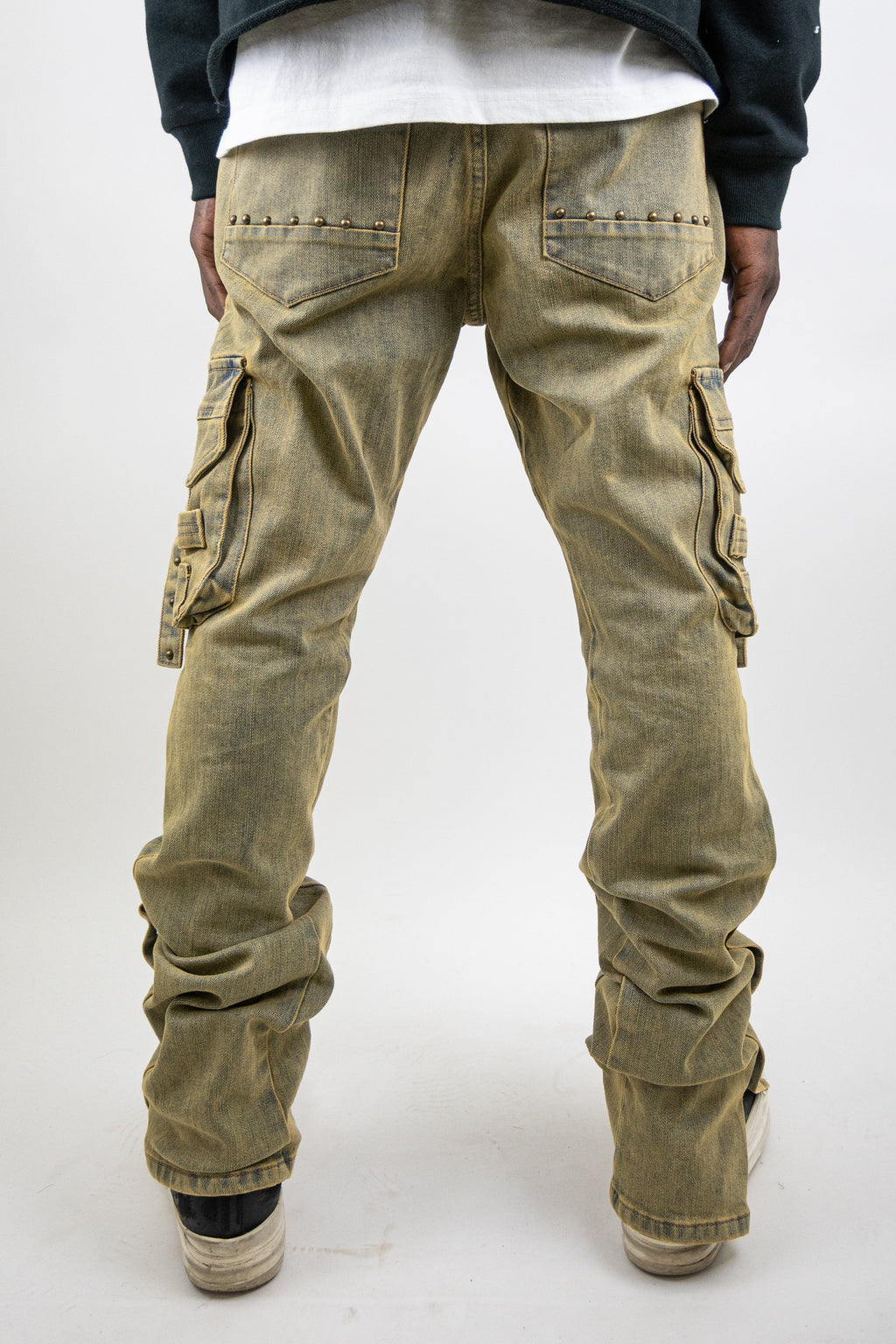 ARMOR JEANS studded stacked cargo jeans, featuring multiple pockets and metal stud accents, laid flat on a neutral background.