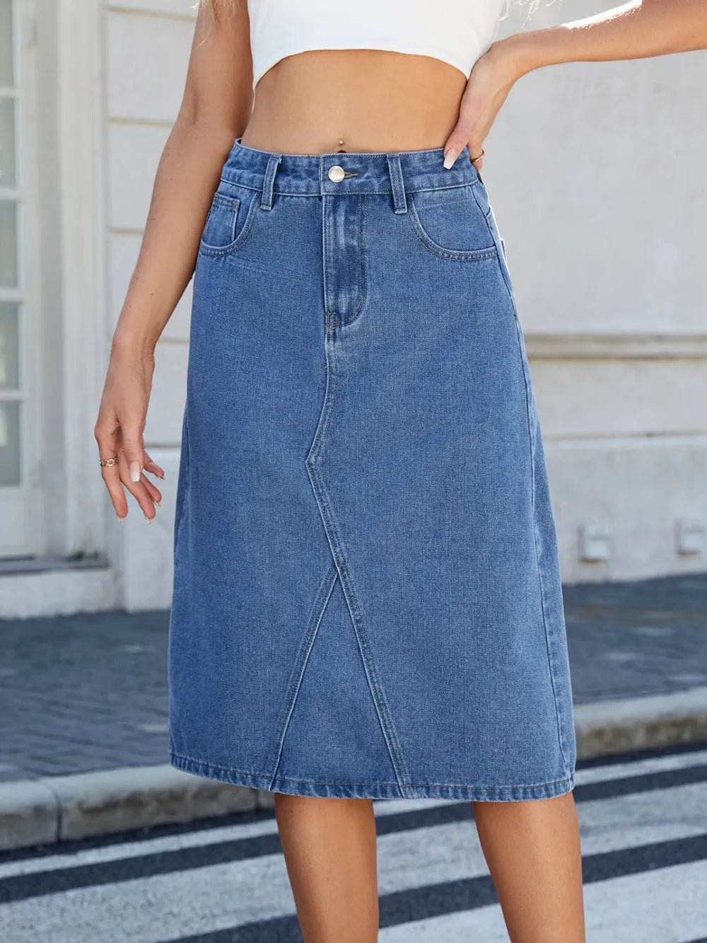 Medium wash blue denim midi skirt with a high waist, front slit, and pockets.