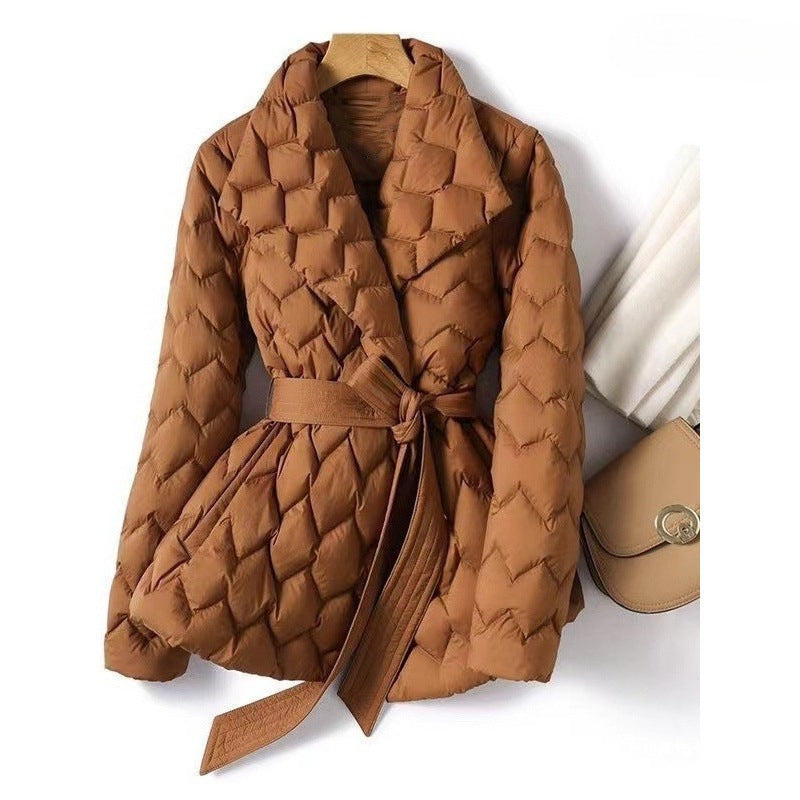 Brown quilted puffer jacket with wide lapels, tie belt, and down material, styled with a purse and scarf.