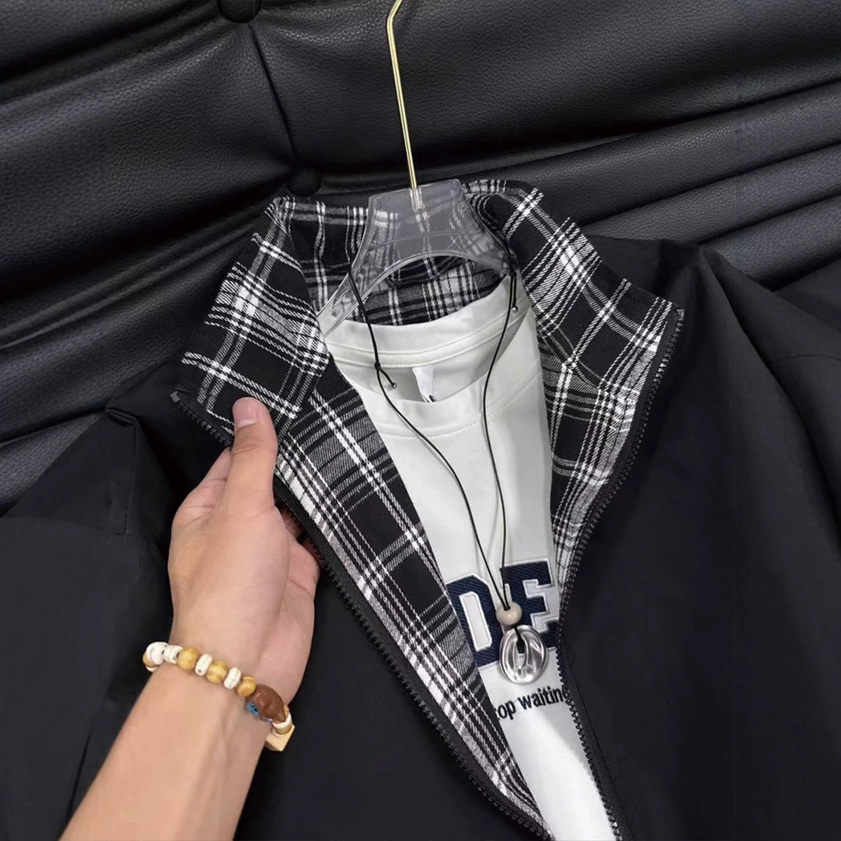 Black jacket with black-and-white plaid collar lining and white t-shirt underneath.