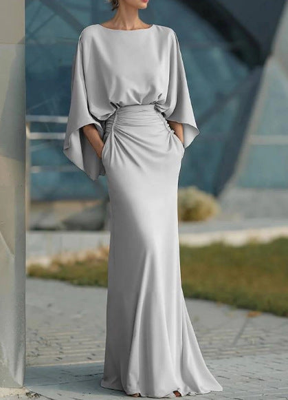 Women's silver backless pleated batwing sleeve maxi dress by FitiqueFit, featuring an elegant mermaid gown design and flowing silhouette.