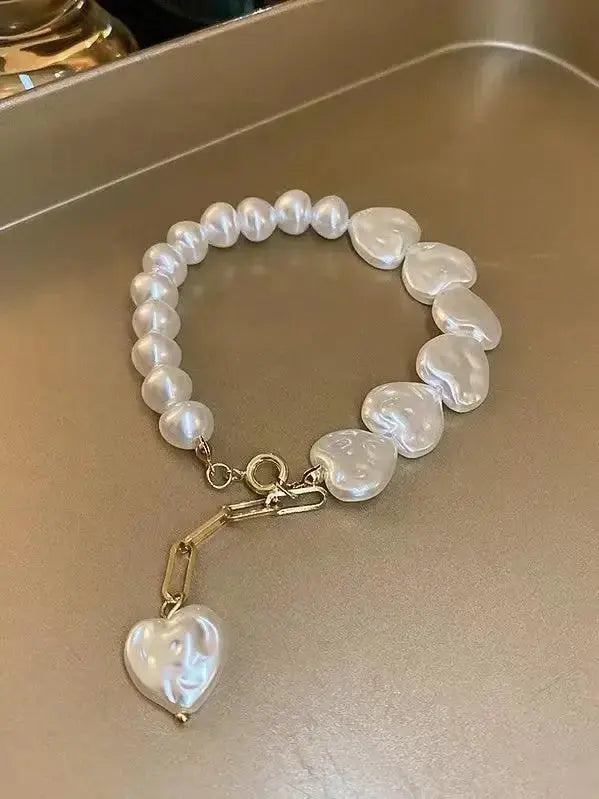Elegant heart-shaped pearl beaded bracelet with stainless steel clasp from Plush Fashion Hub, showcasing a delicate and stylish accessory.