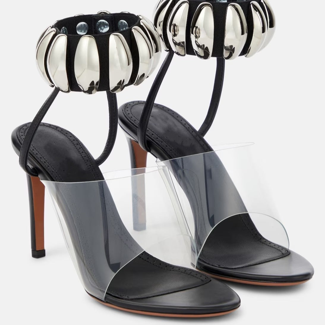 Clear PVC open-toe stilettos with black leather insoles and silver metallic beaded ankle straps.